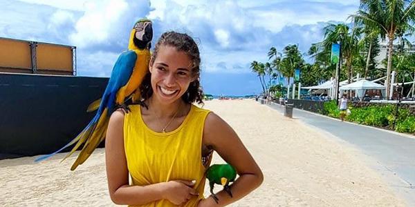 Parrot on shoulder alongside beach